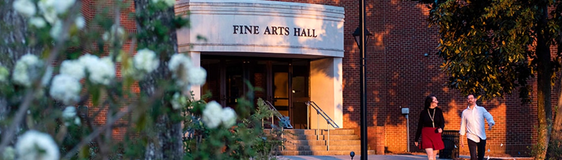 Two people walk in front of Fine Arts Hall